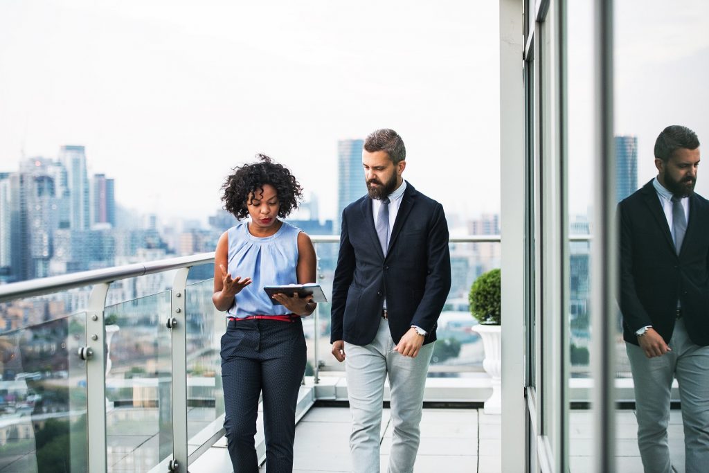 Woman and man on balcony discussing over iPad