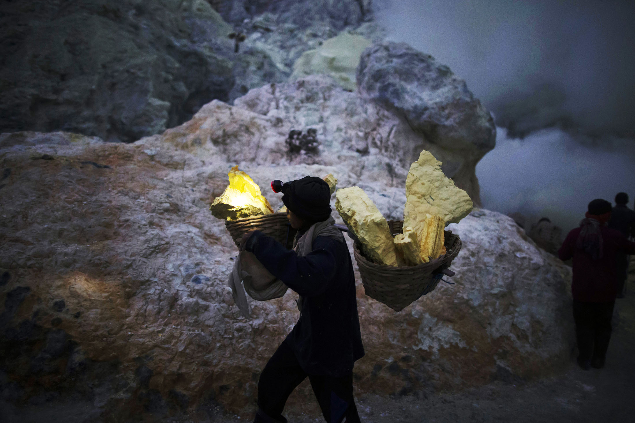 Resultado de imagem para Miners extract the sulfur rock, which is formed after the blue flames